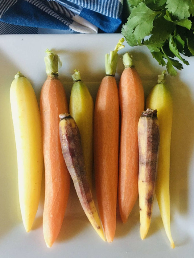 8 Petite Rainbow Carrots sitting on white plate
