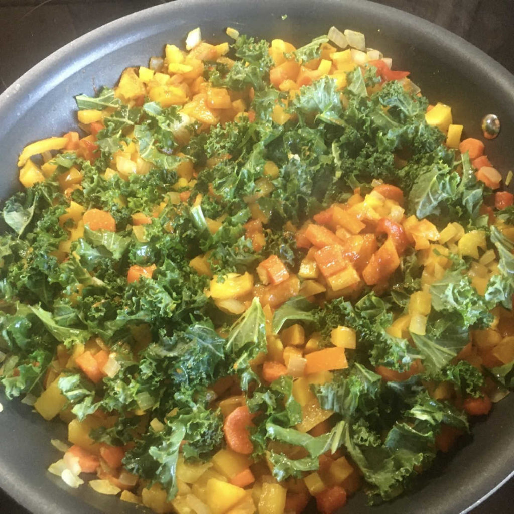 Thai coconut peanut curry with kale cooking in skillet