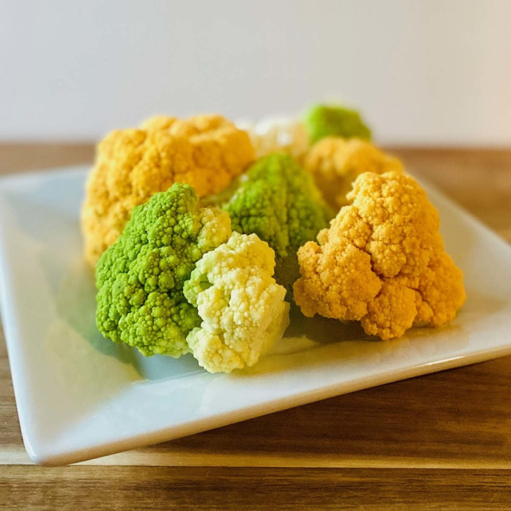 8 tri-color buffalo cauliflower pieces sitting on white plate